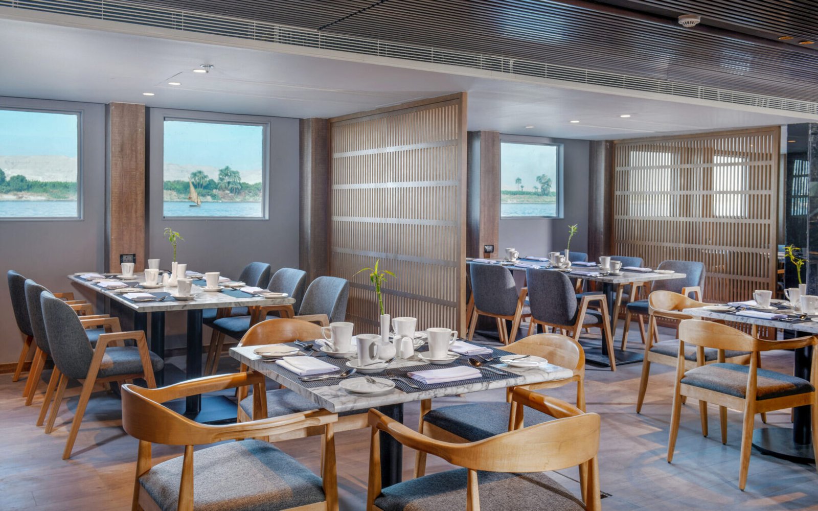 The opulent main dining room of the Historia luxury Nile cruise, with tables elegantly set for a gourmet evening meal