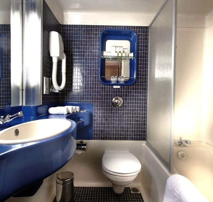 A clean and modern bathroom within a cabin on the Sonesta Nile Goddess, showing a glass-enclosed shower, a well-lit vanity, and fresh towels.