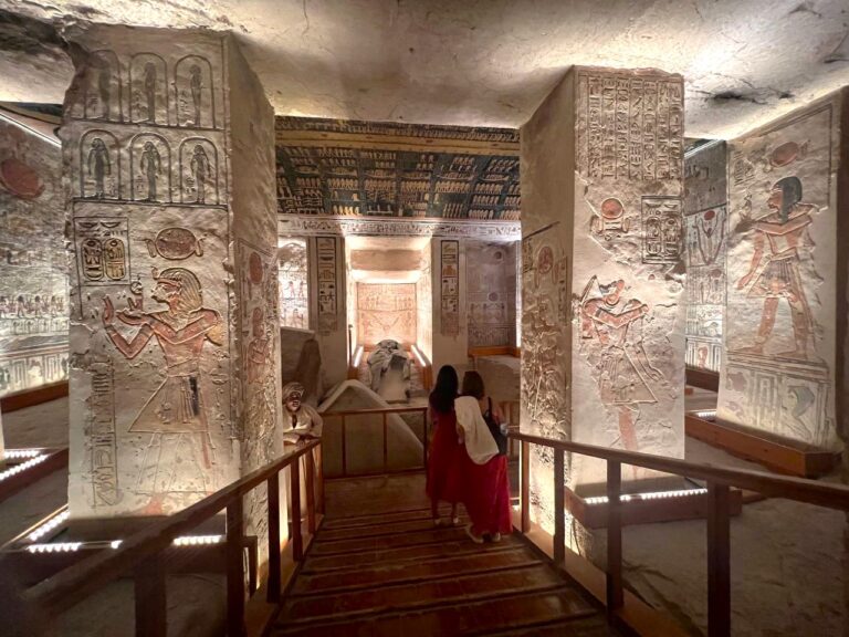 Interior corridor of a New Kingdom pharaoh's tomb, showcasing floor-to-ceiling walls covered in detailed, brightly painted scenes and hieroglyphs.