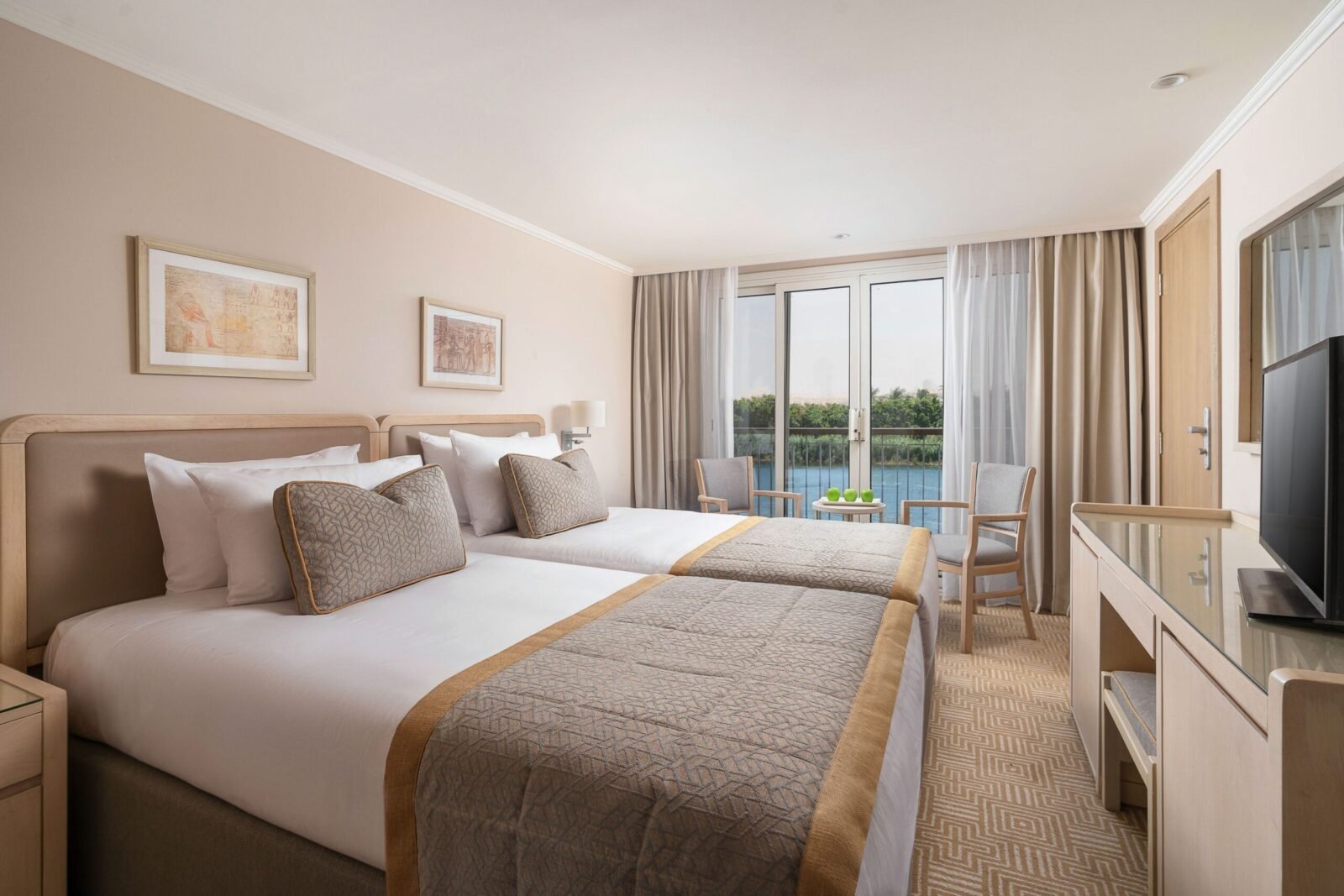 Luxury twin cabin on the Jaz Regent Nile Cruise, featuring two comfortable single beds, elegant furnishings, and a window view of the river.