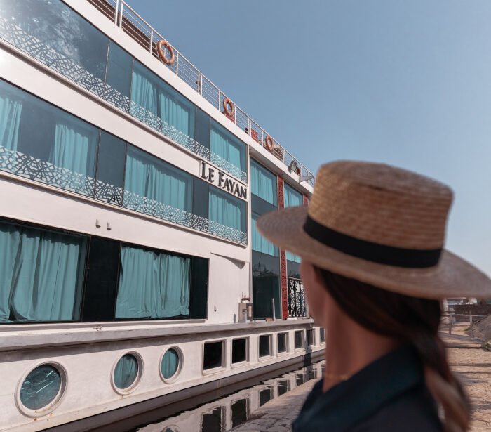 A guest enjoying the luxurious sundeck of the Le Fayan Nile Cruise, with the stunning scenery of the Nile River in the background.