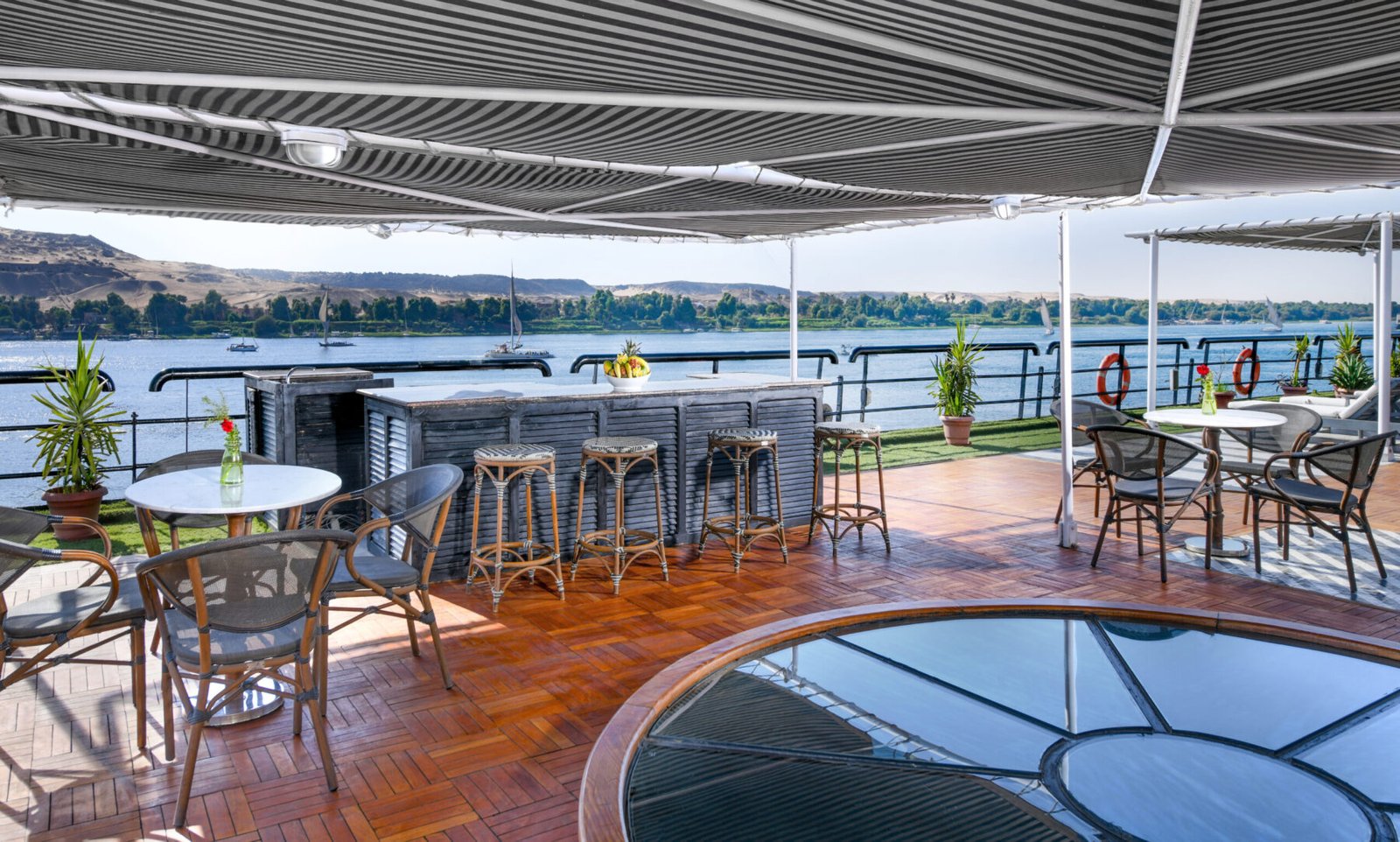 The spacious and shaded sundeck bar on the Movenpick Hamees Nile cruise, featuring comfortable lounge seating with views of the Nile River.