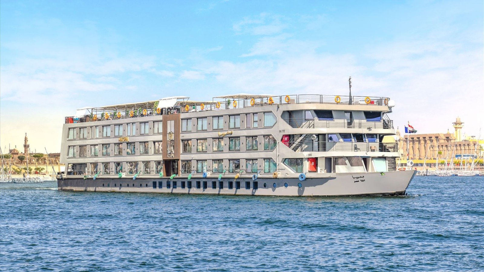 The silhouette of the luxurious Historia Nile cruise ship sailing gracefully on the Nile River during a vibrant Egyptian sunset