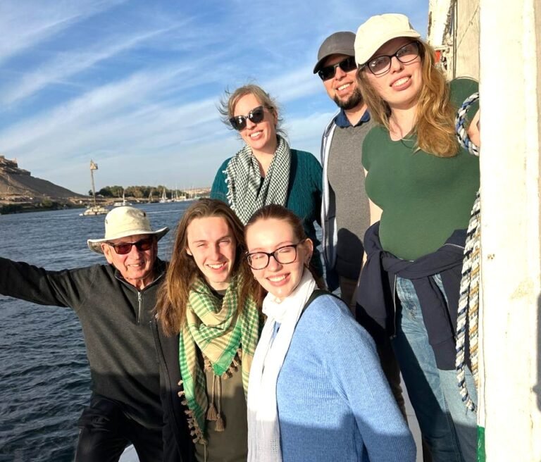 A group of travelers sitting around a table, looking at brochures and talking with a Nile Cruisen representative about booking a Nile cruise tour