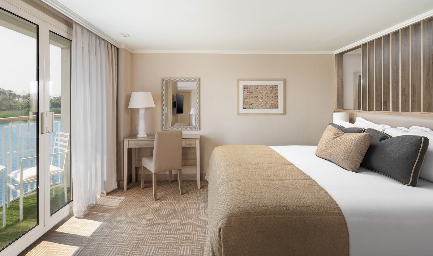 Luxury cabin on the Jaz Viceroy Nile Cruise with a private balcony, floor-to-ceiling glass doors, and a comfortable king-sized bed