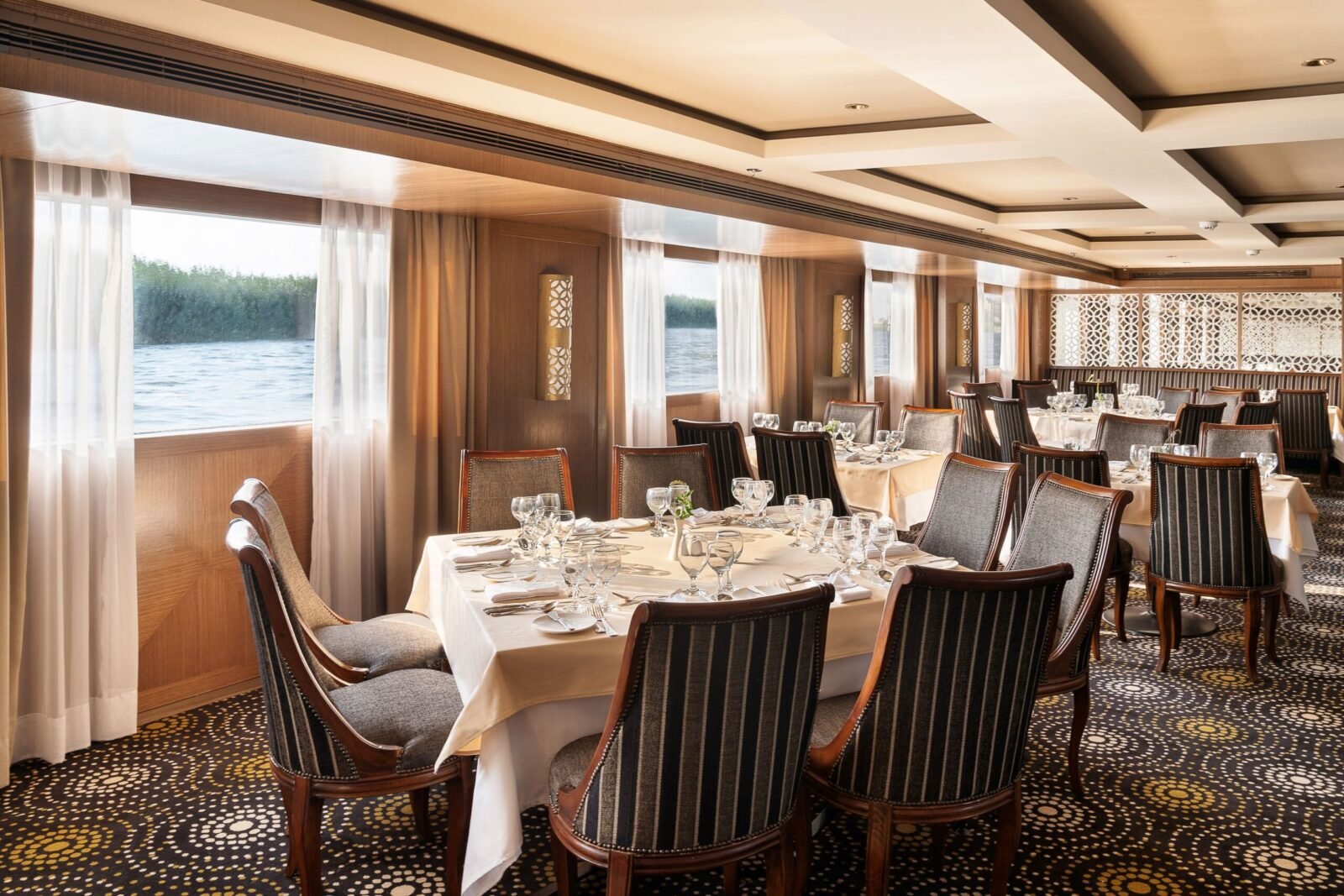 Main dining room of the Jaz Viceroy Nile Cruise, showing buffet stations, set tables, and windows with ambient lighting.