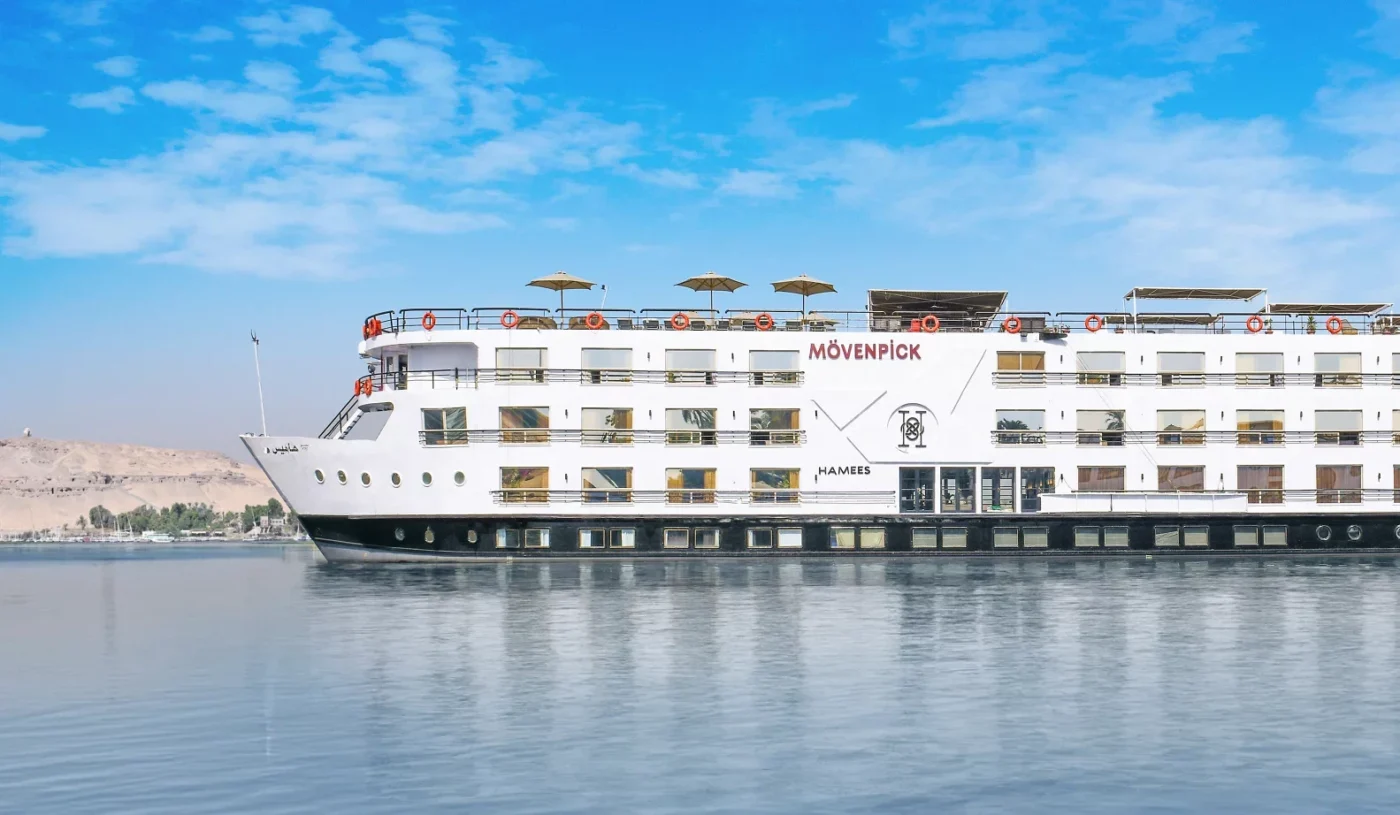 The luxurious Mövenpick MS Hamees Nile cruise ship is sailing on the iconic Nile River, showcasing its modern design and elegant exterior