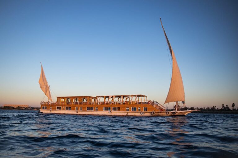 Traditional twin-masted Akhnaton Dahabiya luxury sailboat cruising the Nile River between Luxor and Aswan.