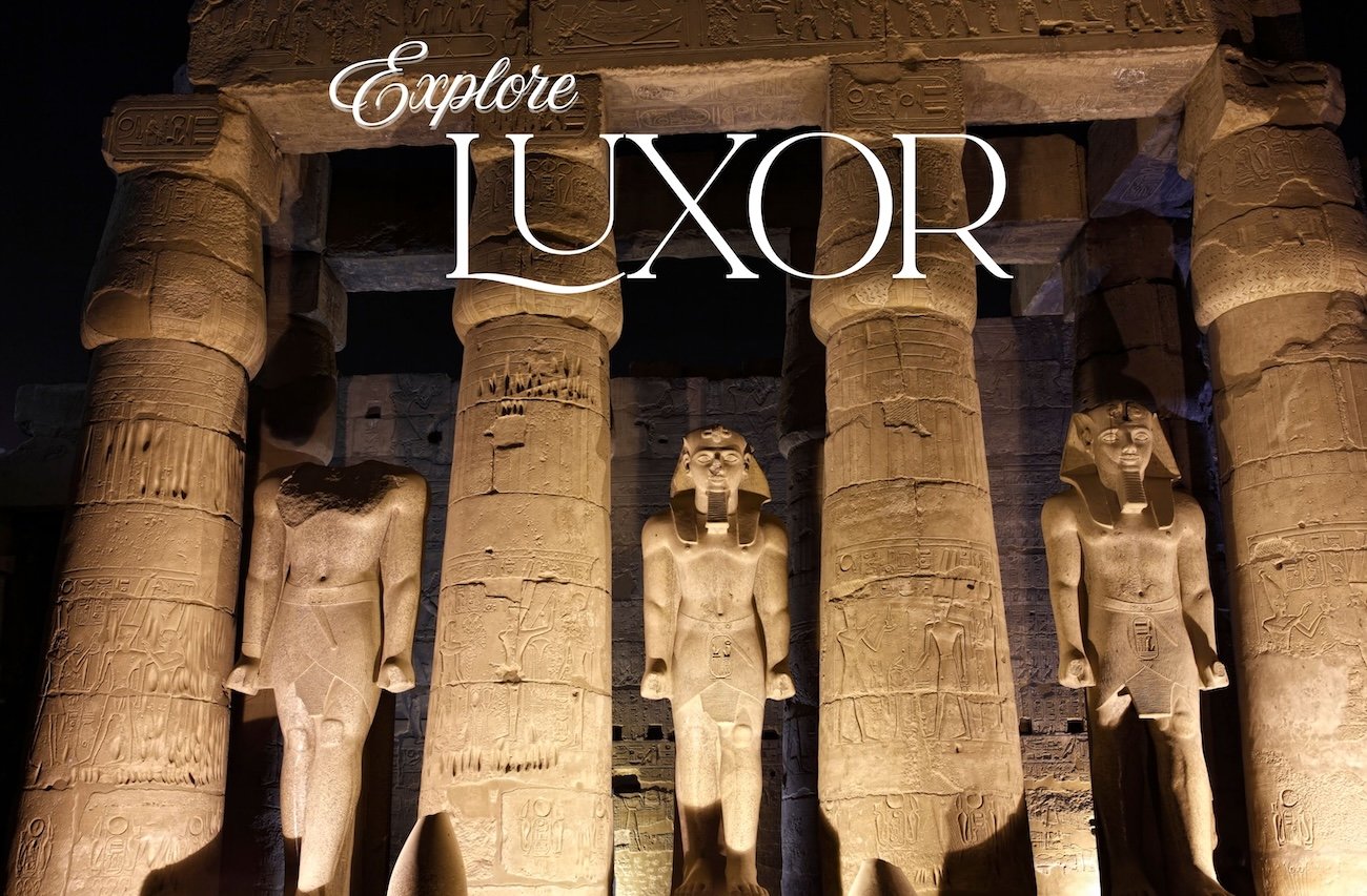 Colossal illuminated statues of King Ramses II standing before the entrance of Luxor Temple at night.