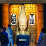 Visitors exploring the Ramses the Great exhibition in London featuring ancient Egyptian artifacts and the statue of Pharaoh Ramses II