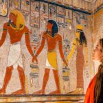 Traveler exploring the colorful ancient wall paintings inside a royal tomb in the Valley of the Kings, Luxor, Egypt with Nile Cruisen