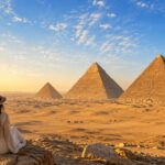 Traveler enjoying a visit to the Great Pyramids of Giza under a clear blue sky in Egypt.